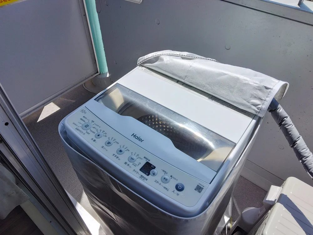 ベランダに洗濯機あり。洗濯カゴあります。