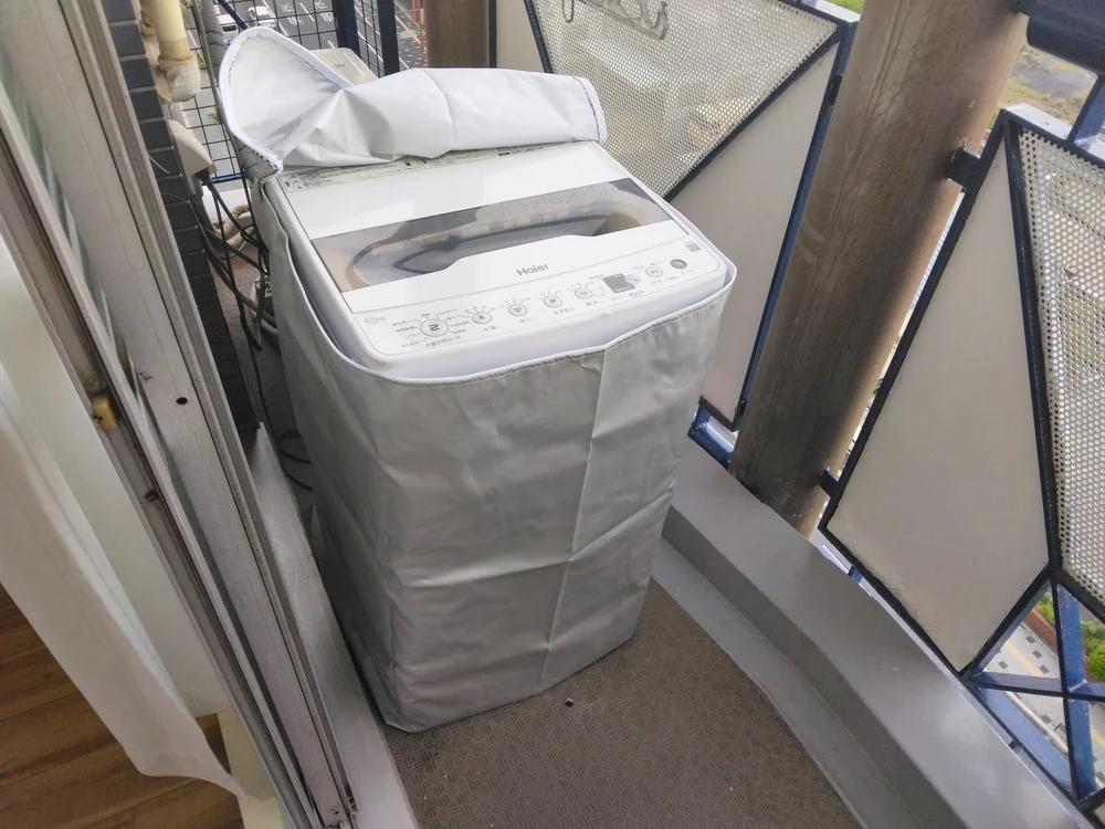 ベランダに洗濯機設置。洗濯物入れのカゴあり。
