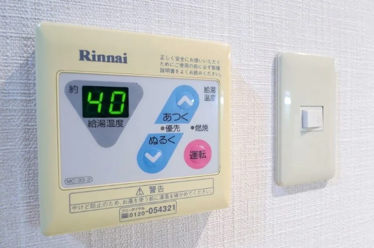 浴室の外からワンタッチで温度調節が可能なスマートな給湯パネル。帰宅後すぐに適温のお湯を準備できるこの小さな利便性の積み重ねが、中長期滞在における『QOL（生活の質）』を密かに、しかし確実に押し上げます。