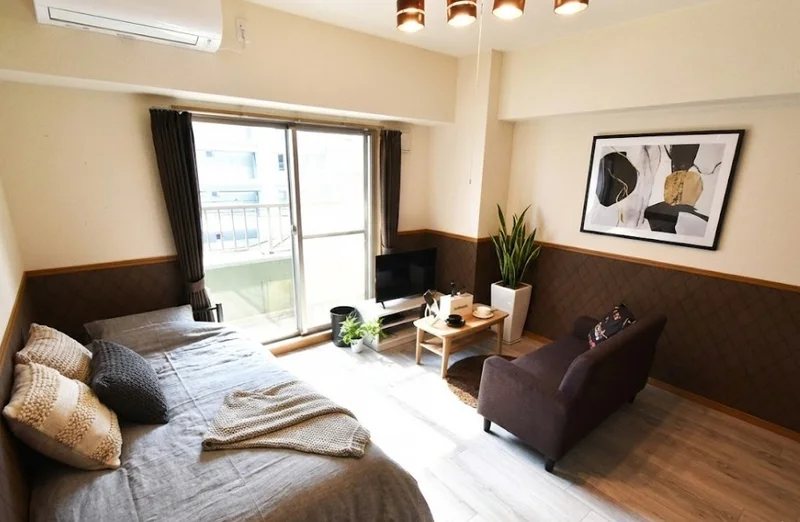 腰壁がシックな感じを漂わす広めの洋室！　大きめのテレビとソファーあり！お仕事終わりなどゆったりお部屋でお過ごしいただけます。※植木と額とクッションなどは写真用です。